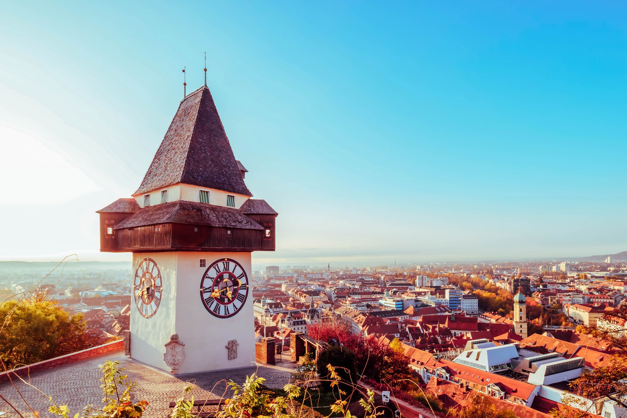 Der Grazer Uhrturm mit Blick über die Stadt Graz im goldenen Licht.
